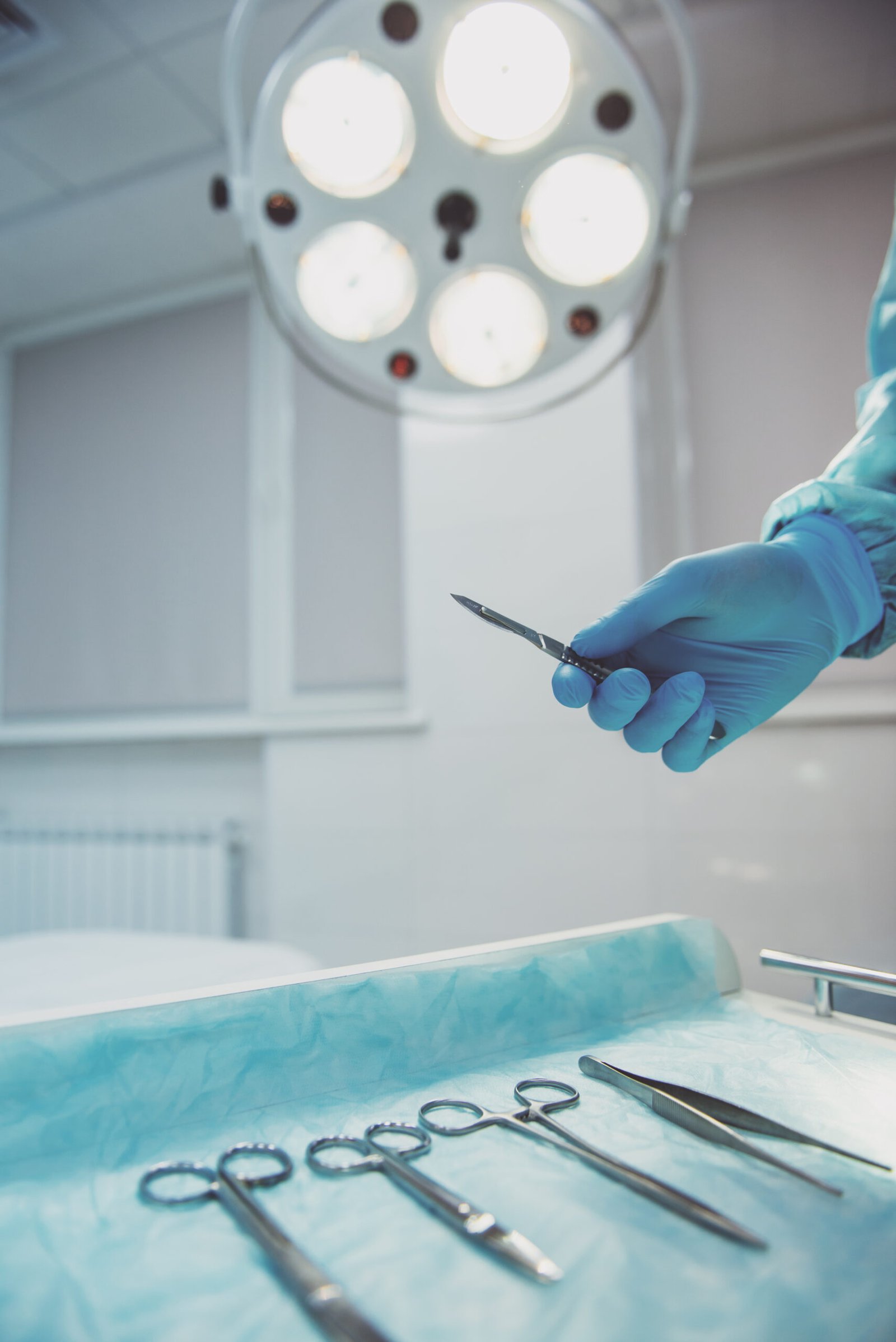 A surgeon is holding a scalpel, close up. Modern operating room in the background